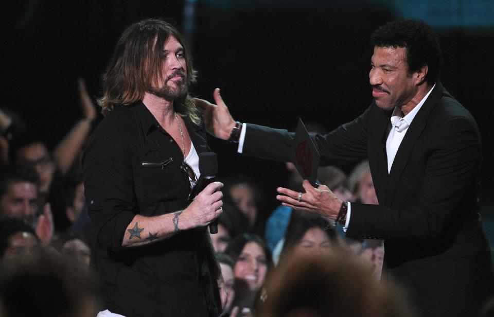 Lionel Richie, right, presents the award for best lyrics to Billy Ray Cyrus, who accepts on behalf of Miley Cyrus at the iHeartRadio Music Awards at the Shrine Auditorium on Thursday, May 1, 2014, in Los Angeles. (Photo by Chris Pizzello/Invision/AP)