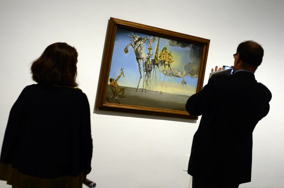 People look at a painting entitled 'The Temptation of St.Anthony' (1946) by Spanish surrealist artist Salvador Dali during the exhibition 'Dali. All of the poetic suggestions and all of the plastic possibilities' at the Reina Sofia museum in Madrid on April 25, 2013. (Photo credit should read JAVIER SORIANO/AFP/Getty Images)