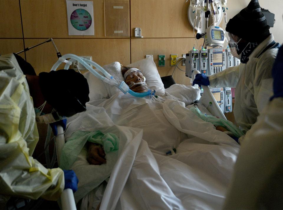 Lorenzo Dominguez Jr., 54, prays for his mother, Etelvina Dominguez, during a visit to Providence Holy Cross Medical Center in Los Angeles on Friday, Feb. 12, 2021. Dominguez and his father, Lorenzo Dominguez Sr., right, were the only family members allowed into the hospital. "The strength, Lord, give me the strength to get through this," Dominguez Jr. said as he got down on his knees. "Give my father the strength. That you send my mom on a peaceful journey. That you wait for her with open arms." Etelvina passed away the next day.