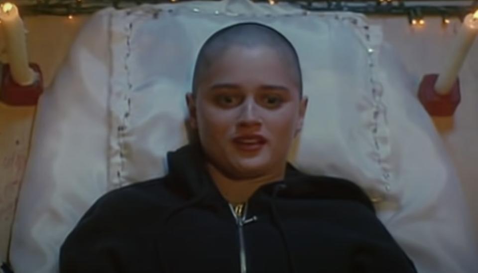 Robin Tunney's head is completely shaved and she wears a black zip up hoodie while laying her head on a pillow.