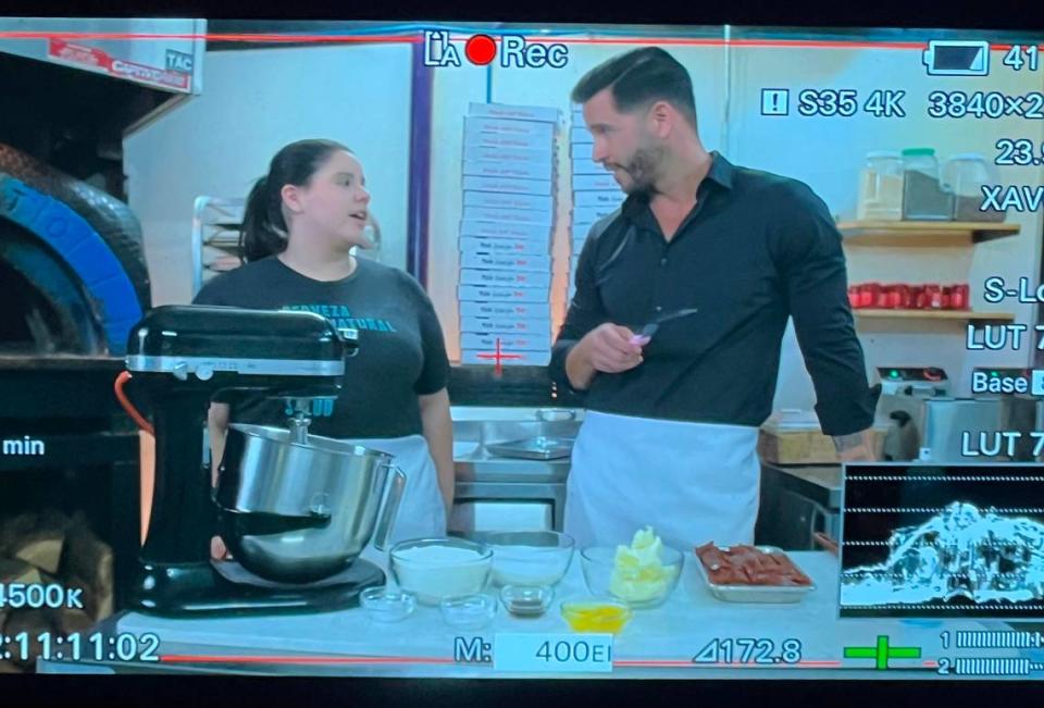 Salud pastry chef Jessica Ceara and “Que Delicia: El Sabor De America” host Jesús Diaz are pictured through a screen during filming of the Charlotte episode.