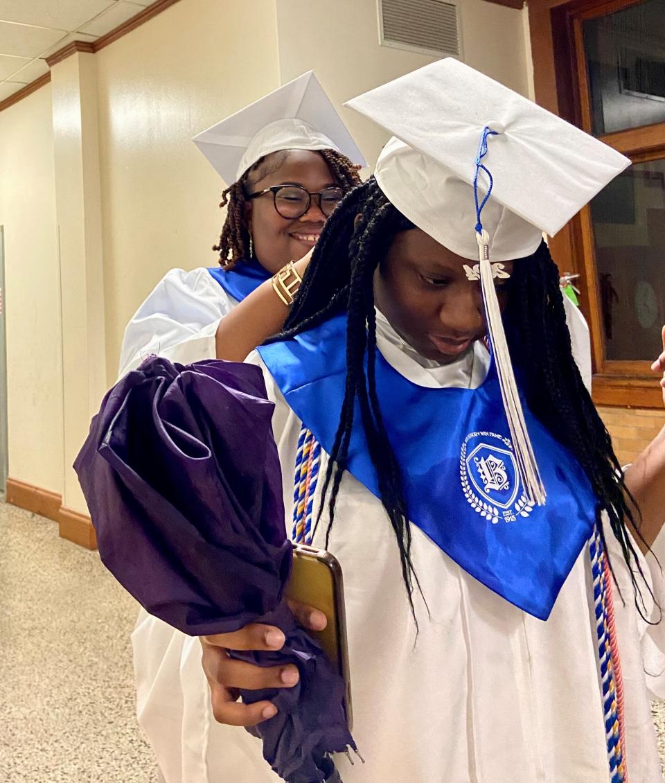 Jayla Allen helps her friend, Ny'Asiah Williams, with her graduation gown before Bolton High School's commencement on Monday. The two, both 18, plan to attend Northwestern State University in the fall.