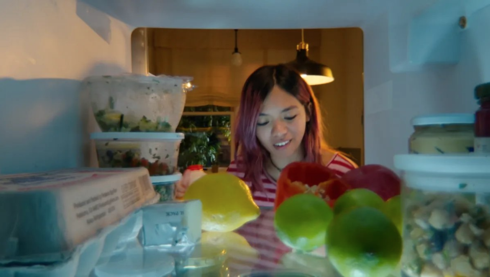 A lady in front of the refrigerator. 