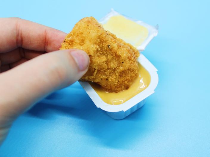 A burger king chicken nugget dipped in honey mustard sauce