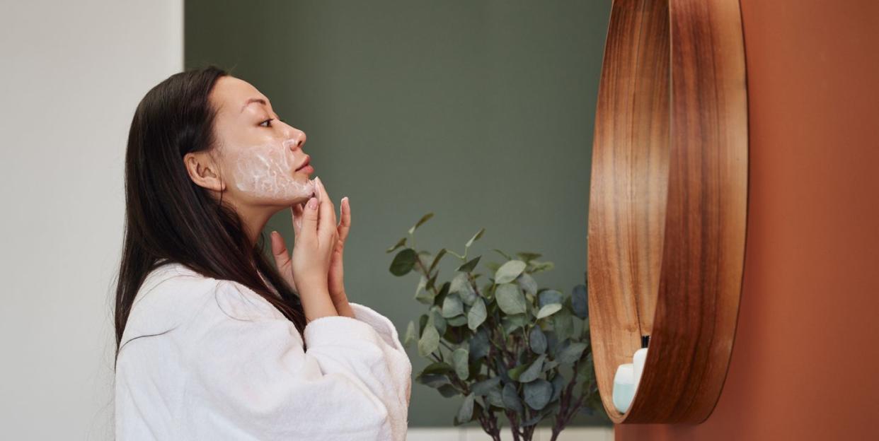 young asian woman applying moisture cream at her face