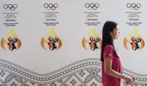 A woman walks past a banner for International Olympic Committee meeting at a convention centre in Kuala Lumpur on July 28, 2015