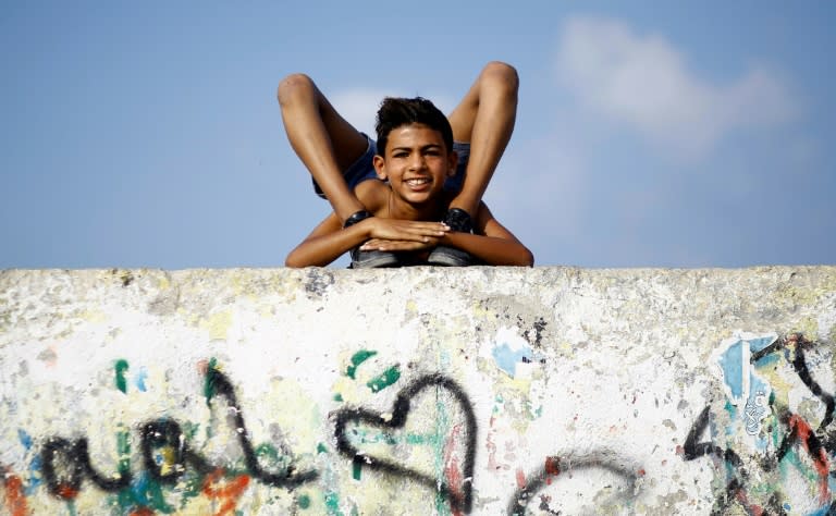 Yousef al-Bahtini, a 12-year-old Palestinian boy aiming for a Guinness World Record for "fastest time to travel 20 metres in a contortion roll", shows off his skills on a wall in Gaza City