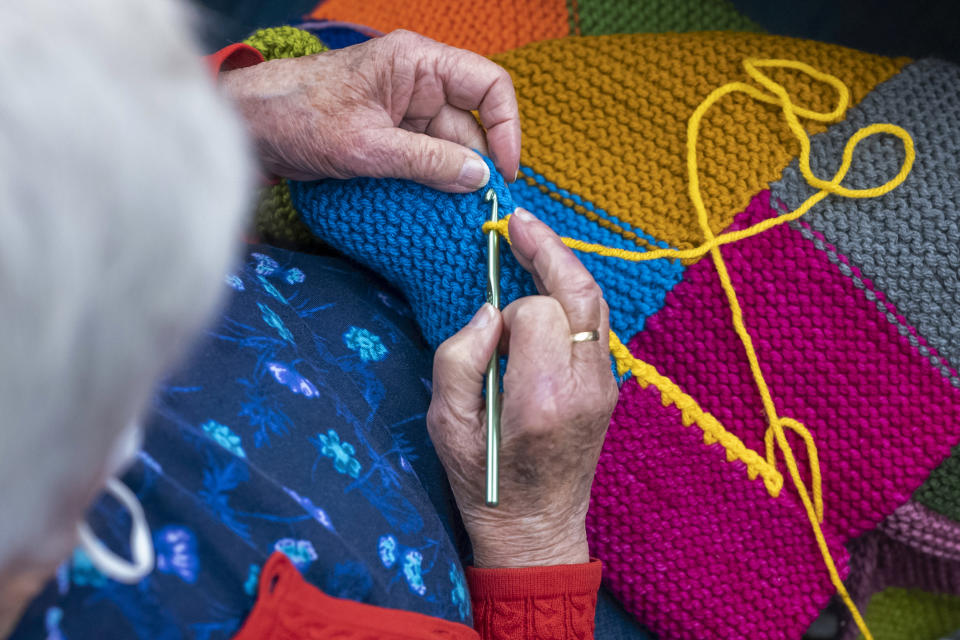 In this photo provided by Edward Boches, a volunteer adds a border to a blanket, Jan. 8, 2023 in Brookline, Mass. The Welcome Blankets will be donated to agencies helping immigrants who recently arrived in the United States. (Edward Boches via AP)