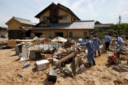 Local residents try to clear mud and debris from a house at a flood affected area in Mabi town in Kurashiki, Okayama Prefecture, July 13, 2018. REUTERS/Issei Kato