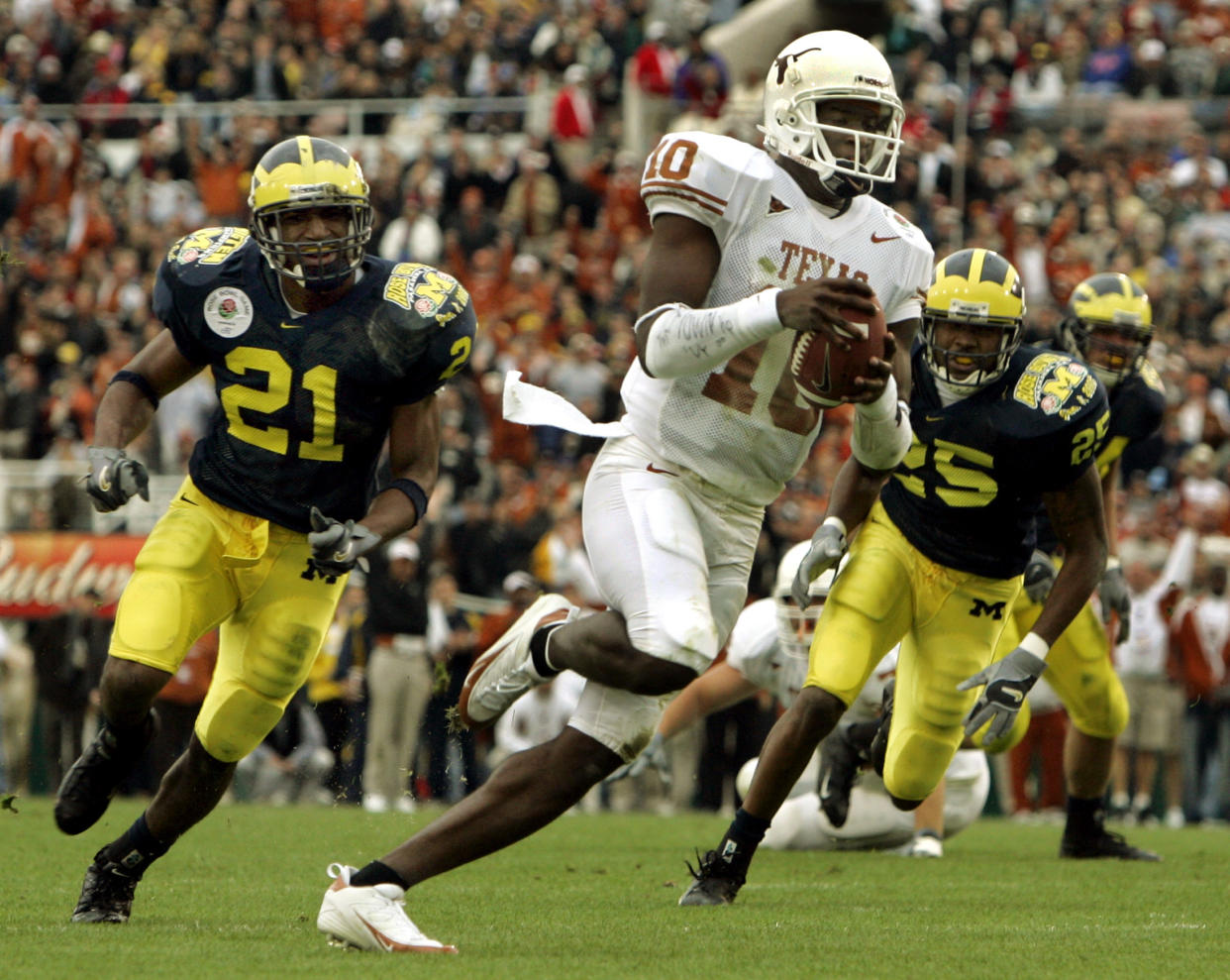 Texas Longhorns quarterback Vince Young (10) sprints 20 yards past Michigan Wolverines free safety Ryan Mundy (L) and safety Ernest Shazor for a touchdown, during the first quarter of the 91st annual Rose Bowl game in Pasadena, California January 1, 2005. REUTERS/Robert Galbraith  RG