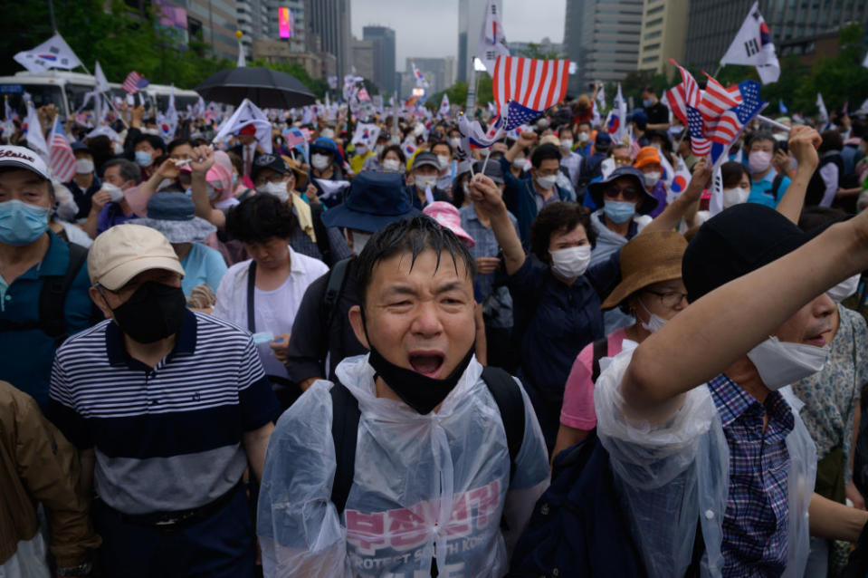 Members of pro-US conservative right-wing and religious christian groups wave flags and shout slogans during an anti-government rally in Seoul on Saturday. Source: Getty