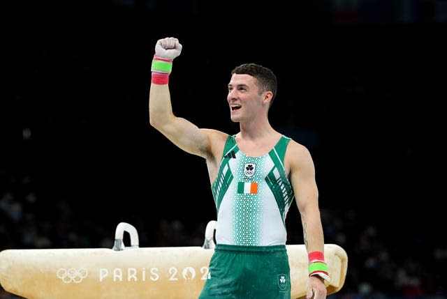 Rhys McClenaghan raises his arm in front of a pommel horse