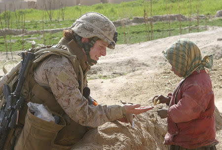 Second Lt. Johanna Shaffer shares a cookie with an Afghan child while under the security of Marines assigned to 3rd Battalion, 8th Marine Regiment (Reinforced), during her all-female team's first mission in Farah Province, February 9, 2009. REUTERS/Monty Burton/U.S. Marine Corps/Handout