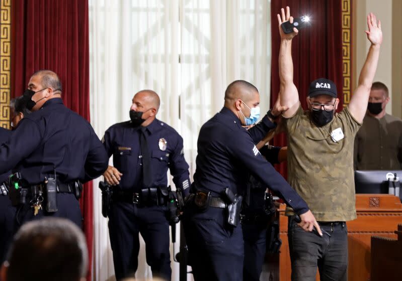 LOS ANGELES, CA - AUGUST 8, 2022 - - Ricci Sergienko, with The People's City Council, is arrested by police officers after crossing a police line in city council chambers at City Hall in Los Angeles on August 8, 2022. Homeless advocates and protesters shut down proceedings in the Los Angeles City Council chambers who had to stop from casting their final vote on a law prohibiting homeless encampments near schools and daycare centers at City Hall on August 8, 2022. Members of the LAPD created a defense line as city council members left chambers. Protesters left the chambers after being threatened with arrest. Two arrests were made during proceedings. (Genaro Molina / Los Angeles Times)