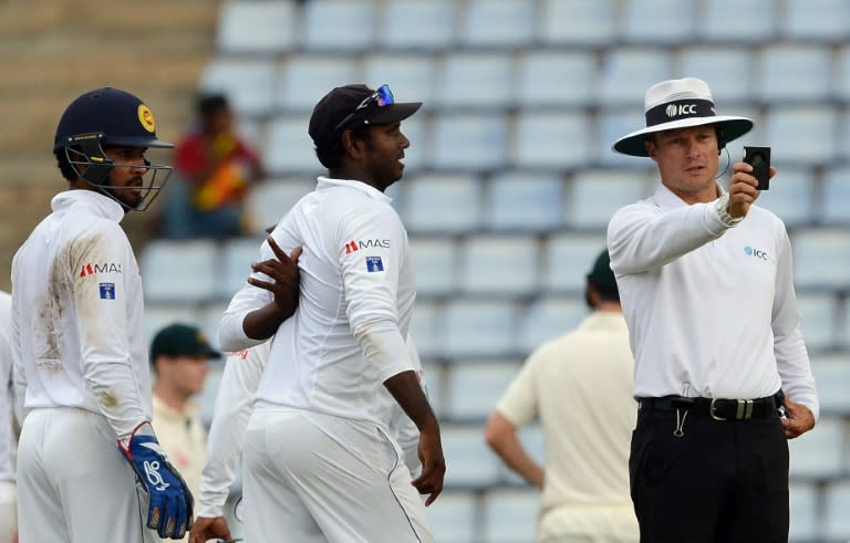 Umpire Richard Kettleborough (R) checks a light meter after bad light stops play during the fourth day of the opening Test between Sri Lanka and Australia in Pallekele on July 29, 2016