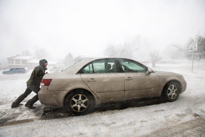 A man helps push a car off the side of Union Blvd. in Colorado Springs, Colo., on Wednesday, March 13, 2019. Some of Colorado's busiest highways are closed as a raging storm brings heavy snow to a wide swath of the West and Midwest. Many schools and state offices were shut down Wednesday amid a blizzard expected to engulf parts of Colorado, Wyoming, Montana, Nebraska and South Dakota. (Kelsey Brunner/The Gazette via AP)