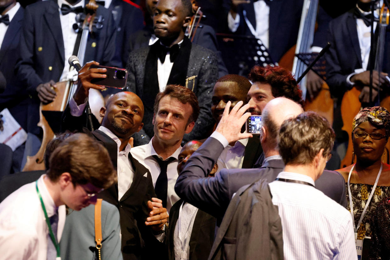 Une bière avec Macron en RDC ? Ce ministre congolais s’explique après un apéro très commenté (Photo d’Emmanuel Macron prenant des selfies avec des spectateurs présents au concert du Kinshasa Symphonic Orchestra le 4 mars 2023 )