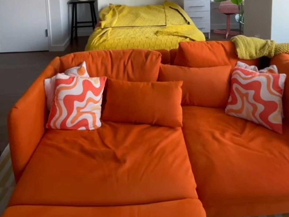 An orange couch with groovy dark-orange and light-orange throw pillows