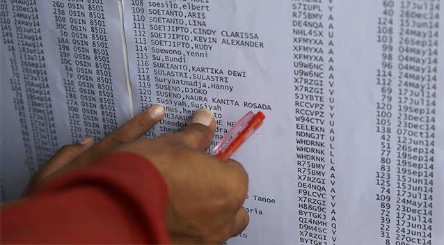 Relatives point at the name of their family member on a list of passengers onboard AirAsia flight QZ8501 at Juanda International Airport in Surabaya. Photo: AP