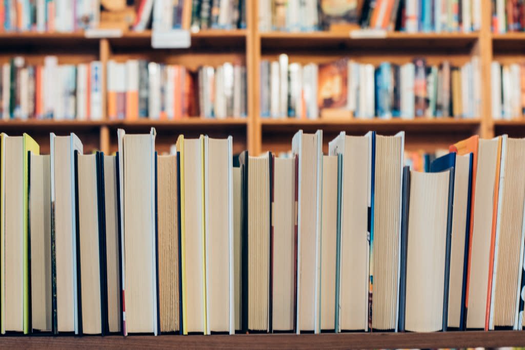 Line of books from the side with library shelves of books behind them