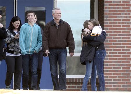 Students of Arapahoe High School hug as others smile while leaving Euclid Middle School, one of the reunification centers, with their families in Centennial, Colorado