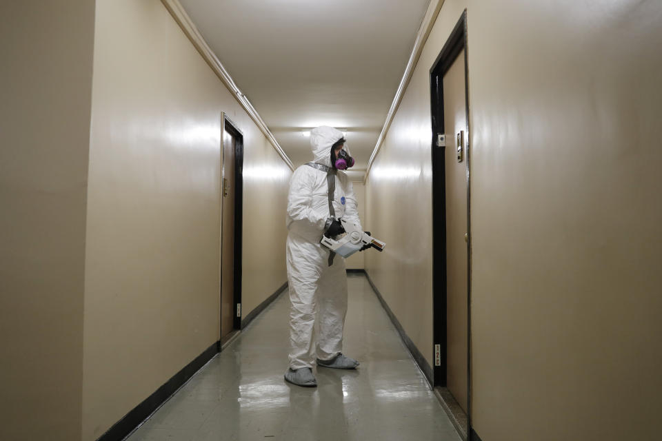 Safety Director Tony Barzelatto sprays disinfectant in a hallway of a building in Co-op City in the Bronx borough of New York, Wednesday, May 13, 2020. Regular cleanings occur throughout the common areas of the buildings while the heavy disinfecting occurs in response to specific incidents, in this case reports of two coronavirus cases on the same floor. Within the Bronx, almost no place has been hit as hard as Co-op City. (AP Photo/Seth Wenig)