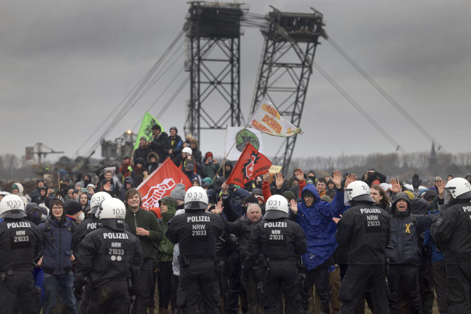 Police officers block demonstrators on the edge of the opencast lignite mine Garzweiler at the village Luetzerath near Erkelenz, Germany, Saturday, Jan. 14, 2023. ( Oliver Berg/dpa via AP)