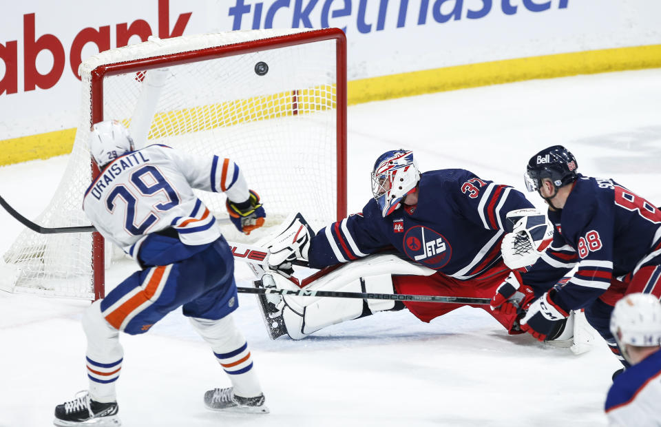 Edmonton Oilers' Leon Draisaitl (29) scores on Winnipeg Jets goaltender Connor Hellebuyck (37) as Nate Schmidt (88) defends during the second period of an NHL hockey game Tuesday, March 26, 2024, in Winnipeg, Manitoba. (John Woods/The Canadian Press via AP)