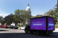 A video sign about Facebook is shown on a truck at the State Capitol during a rally in Lansing, Mich., Wednesday, May 20, 2020. Barbers and hair stylists are protesting the state's stay-at-home orders, a defiant demonstration that reflects how salons have become a symbol for small businesses that are eager to reopen two months after the COVID-19 pandemic began. (AP Photo/Paul Sancya)