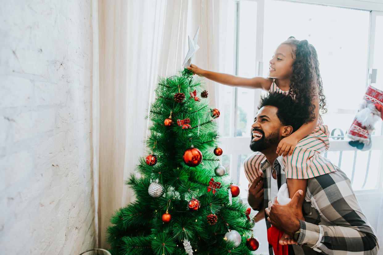 Father and daughter decorating Christmas tree switch off