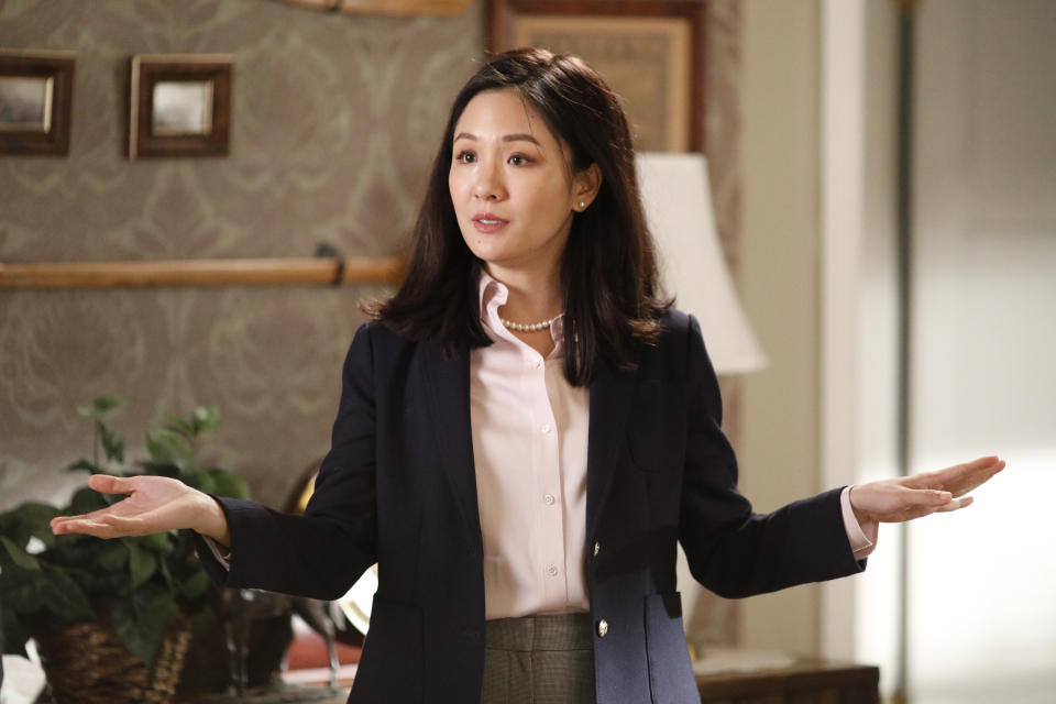 Constance Wu wearing a business suit with hands outstretched in a scene from Fresh Off the Boat