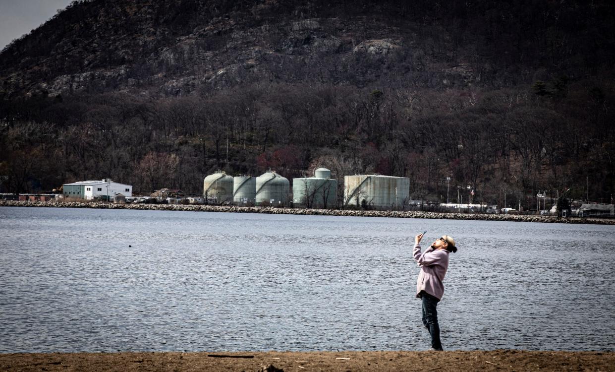 A woman photographs the eclipse at Riverfront Green Park in Peekskill April 8, 2024.