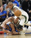 Milwaukee Bucks forward Khris Middleton, right, goes over teammate center Brook Lopez and Orlando Magic guard Jalen Suggs, left, chasing a loose ball during the second half of an NBA basketball game, Sunday, April 14, 2024, in Orlando, Fla. (AP Photo/John Raoux)