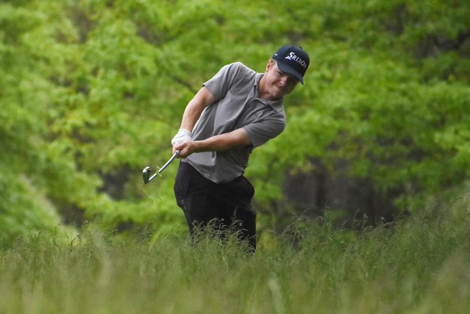 Howell senior Ethan Satterly hits out of the weeds on the left side of the 10th fairway during the KLAA postseason golf tournament Thursday, May 26, 2022 at Kensington Metropark Golf Course.