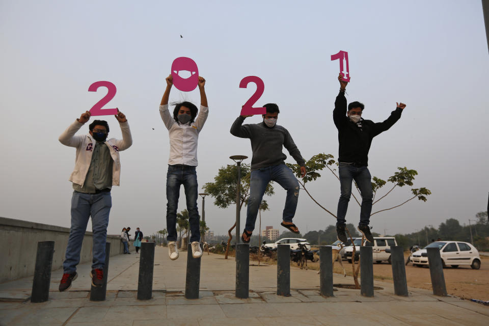 People hold cutouts to welcome the New Year in Ahmedabad, India, Thursday, Dec. 31, 2020. (AP Photo/Ajit Solanki)