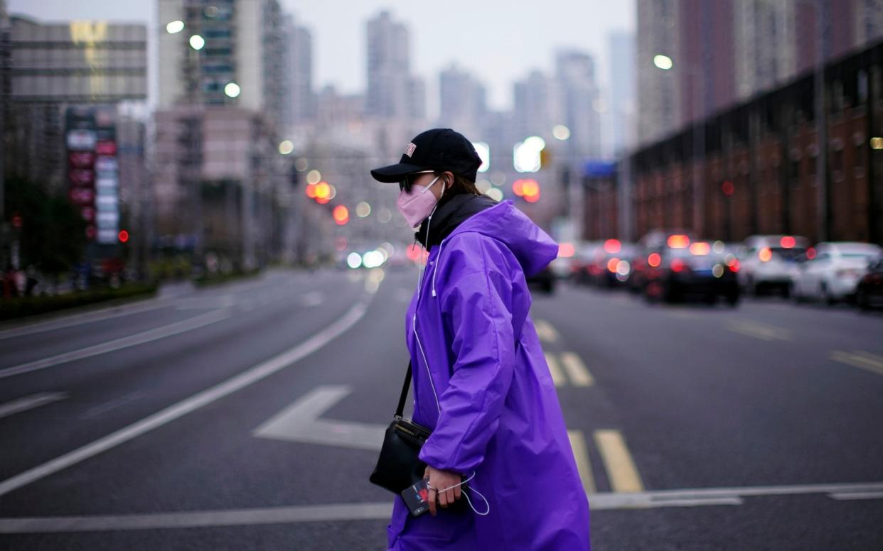 A woman wearing a face mask is seen on a street in downtown Shanghai - ALY SONG / REUTERS