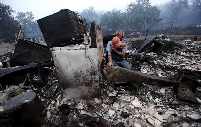 Sheri Marchetti-Perrault and James Benton embrace as they sift through the remains of their home.