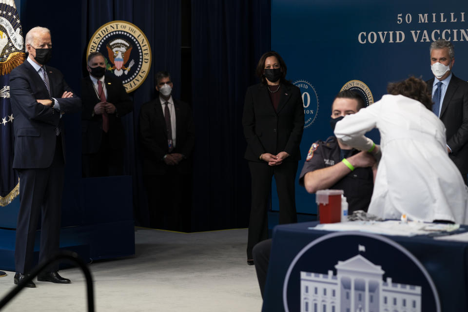 President Joe Biden looks on as DC firefighter and EMT Corey Hamilton receives a vaccination, during an event to commemorate the 50 millionth COVID-19 shot, in the South Court Auditorium on the White House campus, Thursday, Feb. 25, 2021, in Washington. Vice President Kamala Harris and White House COVID-19 Response Coordinator Jeff Zients look on. (AP Photo/Evan Vucci)