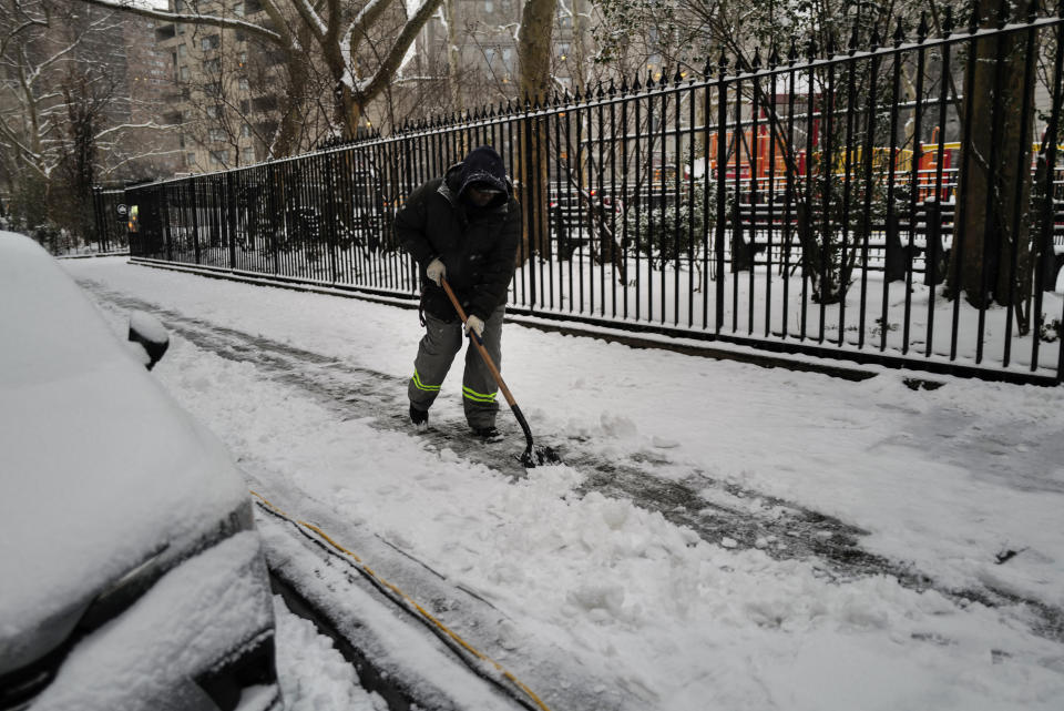 A city worker shovels snow from a sidewalk in Manhattan.