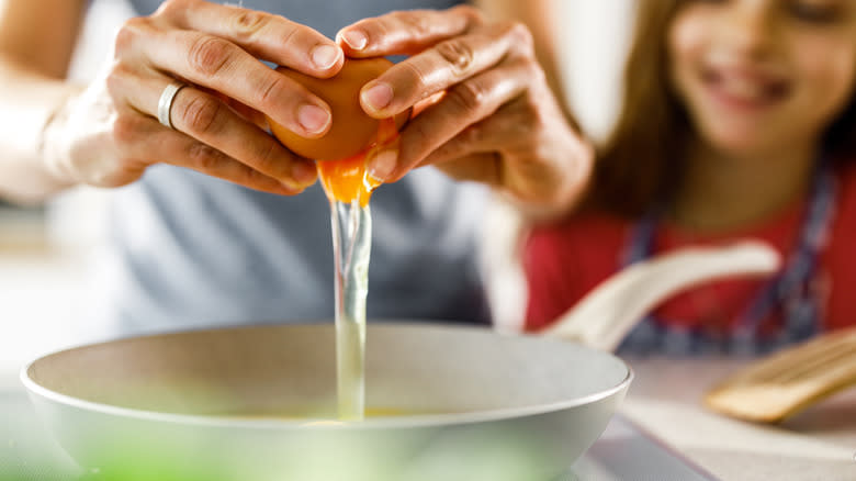 person cracking egg bowl