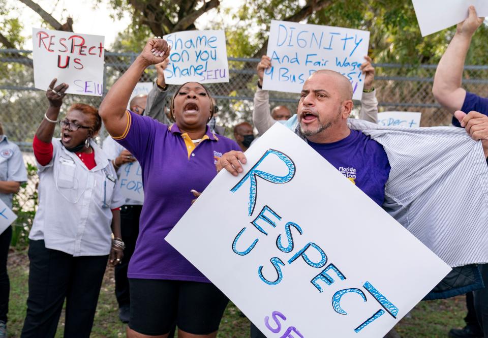 Palm Beach County School bus drivers, Jose Soto (right) and Rhonda Miller (center) join others to protest in West Palm Beach Wednesday. With a shortage of bus drivers, they are frustrated and asking for more money for the extra routes they have to run and want to work with management to make the routes run more smoothly.