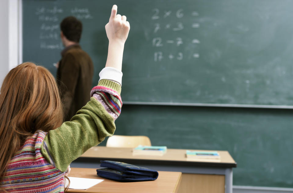 girl with hand up in classroom