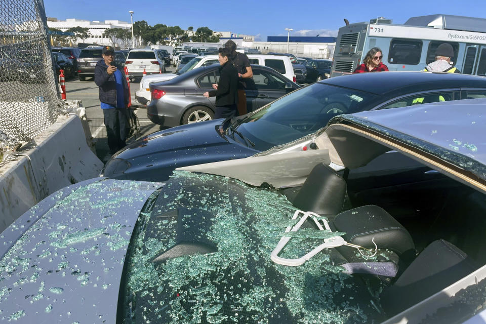 People view damaged cars in an on-airport employee parking lot after tire debris from a Boeing 777 landed on them at San Francisco International Airport, Thursday, March 7, 2024. A United Airlines jetliner bound for Japan made a safe landing in Los Angeles on Thursday after losing a tire while taking off from San Francisco. (AP Photo/Haven Daley)