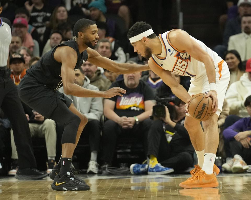 Phoenix Suns guard Devin Booker (1) is defended by Brooklyn Nets forward Mikal Bridges (1) during the first quarter at Footprint Center in Phoenix on Dec. 13, 2023.