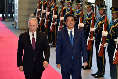 Russian President Vladimir Putin (L) and Japanese Prime Minister Shinzo Abe review an honor guard before their working lunch at Abe's official residence in Tokyo, Japan, December 16, 2016. REUTERS/Frank Robichon/Pool