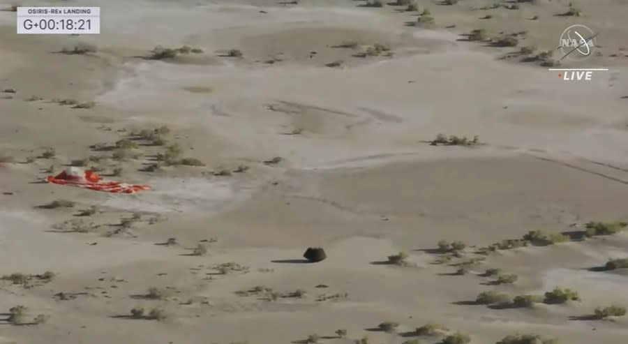 This image shows the capsule released by the OSIRIS-REx spacecraft lying on the surface near the parachute after landing to Earth. (NASA TV via AP)