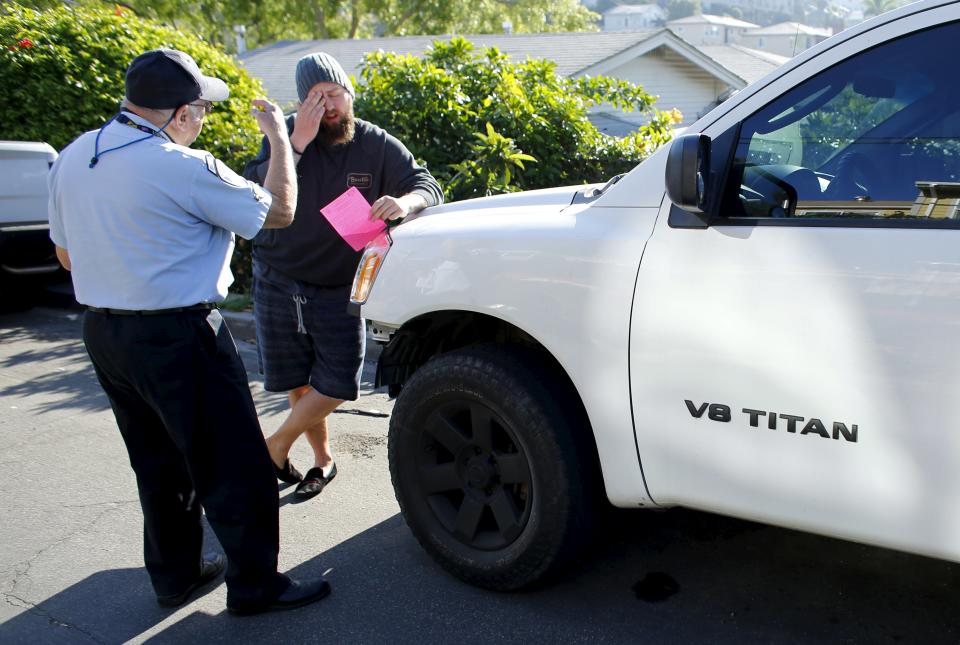 88-year-old Retired Senior Volunteer Patrol member Ed Robles (L) explains parking regulations to the roommate of a truck owner, while on patrol in San Diego, California, United States March 10, 2015. (REUTERS/Mike Blake)