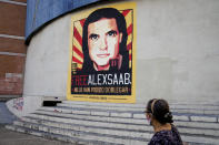 A pedestrians walks near a poster asking for the freedom of Colombian businessman and Venezuelan special envoy Alex Saab, in Caracas, Venezuela. Saturday, Oct. 16, 2021. Saab, a top fugitive close to Venezuela's socialist government has been put on a plane from Cape Verde to the U.S. to face money laundering charges, a senior U.S. official confirmed Saturday. 2021. (AP Photo/Ariana Cubillos)