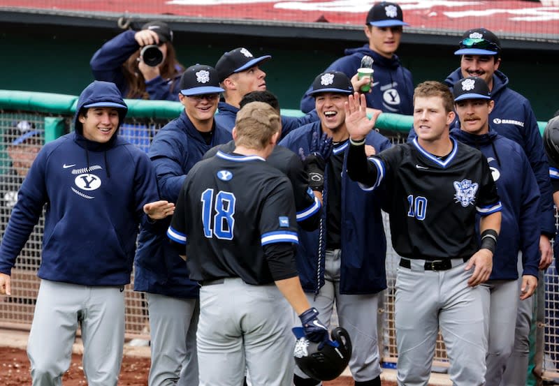 The BYU Cougars, wearing blue, celebrate at the dugout