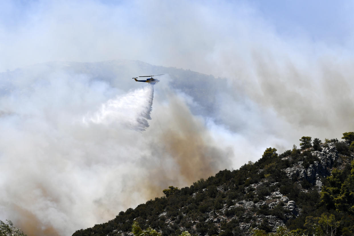 A helicopter drops water over a fire in Nea Makri, east of Athens, on Monday.